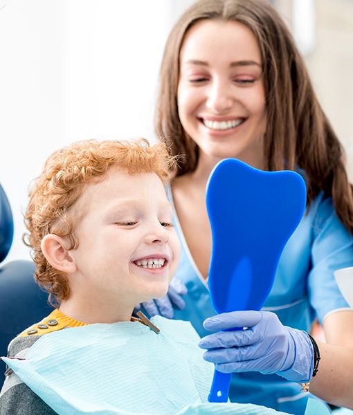 Child looking at smile in mirror during dental checkups and teeth cleanings visit