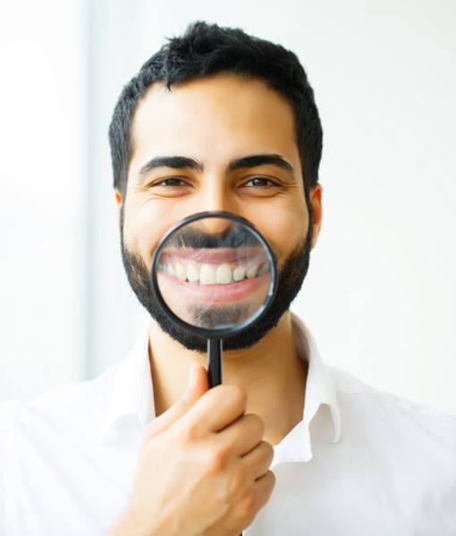 man holding magnifying glass to his smile