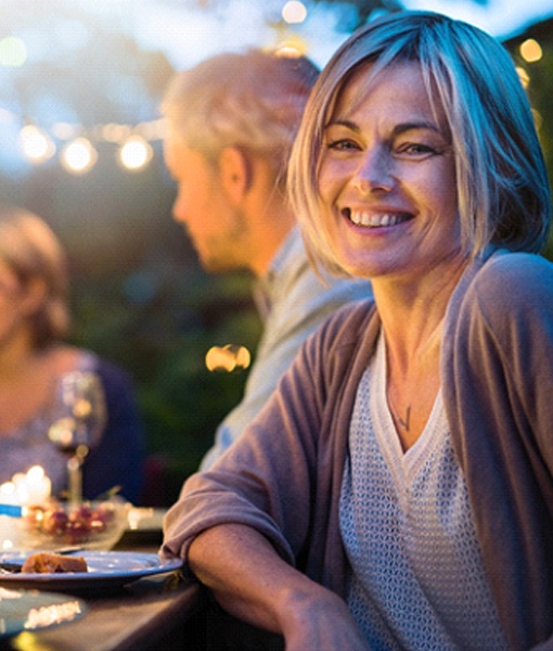 Woman with dental bridge in Edmonton smiling at dinner party