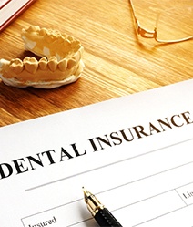 Dental insurance form on desk, next to glasses and dental mold