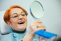 An older woman admiring her dentures