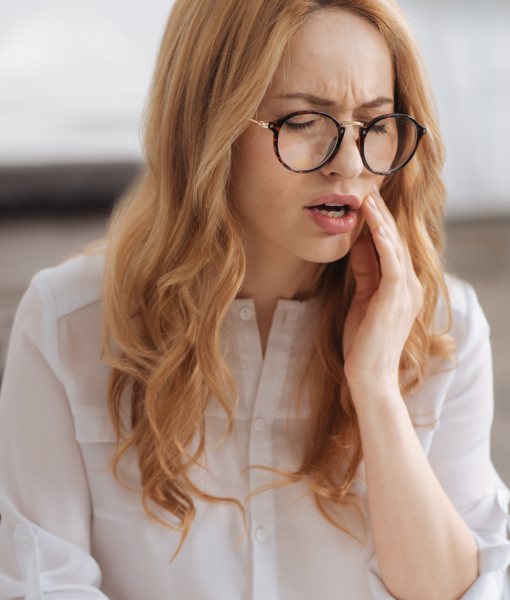 Woman in need of emergency dentistry holding cheek in pain