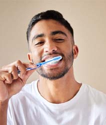 Man with dental implants in Edmonton, Canada brushing his teeth