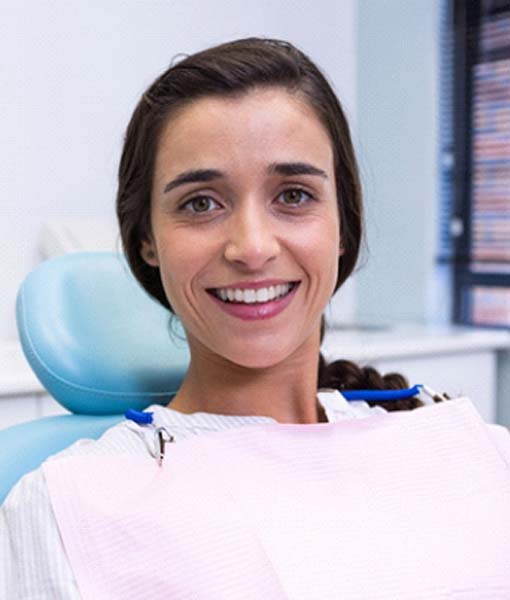 Smiling woman sitting in dental chair with dental implants in Edmonton, AB
