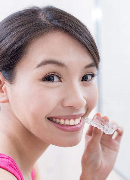 Smiling woman holding an Invisalign tray