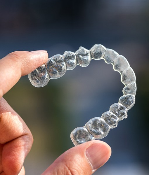 Hand holding an Invisalign tray