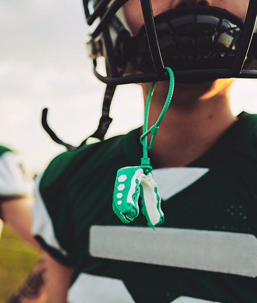 Teen boy with athletic mouthguard hanging from football helmet