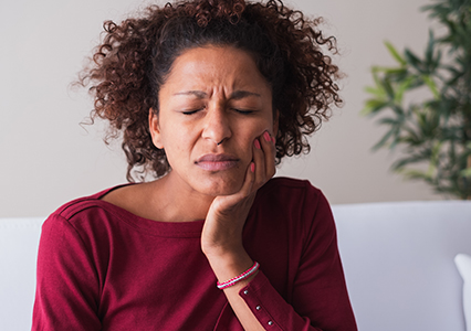 Woman in need of wisdom tooth extraction holding cheek