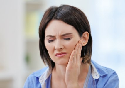 Woman in need of emergency dentistry holding cheek in pain