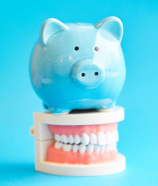 Piggy bank atop model teeth representing the cost of veneers in Edmonton 